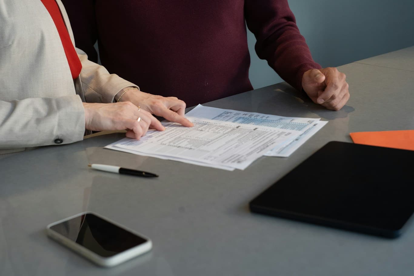 Deux personnes examinent des documents à une table de travail.