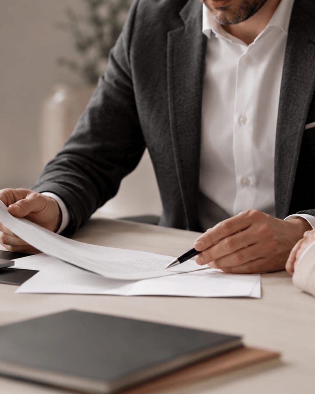 Deux personnes examinent un document de part et d’autre d’une table de travail.