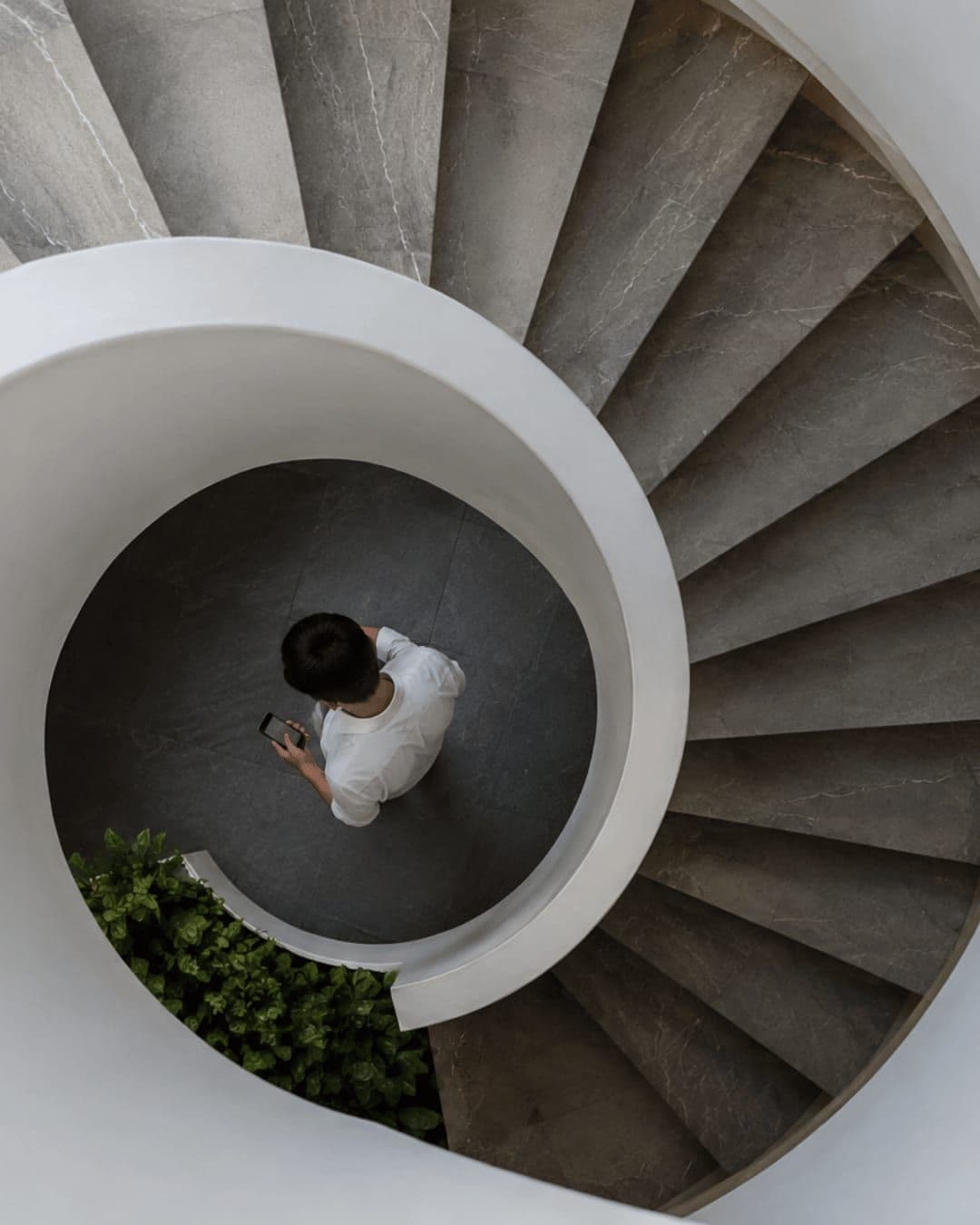 Un escalier hélicoïdal vu du dessus, une personne au centre.